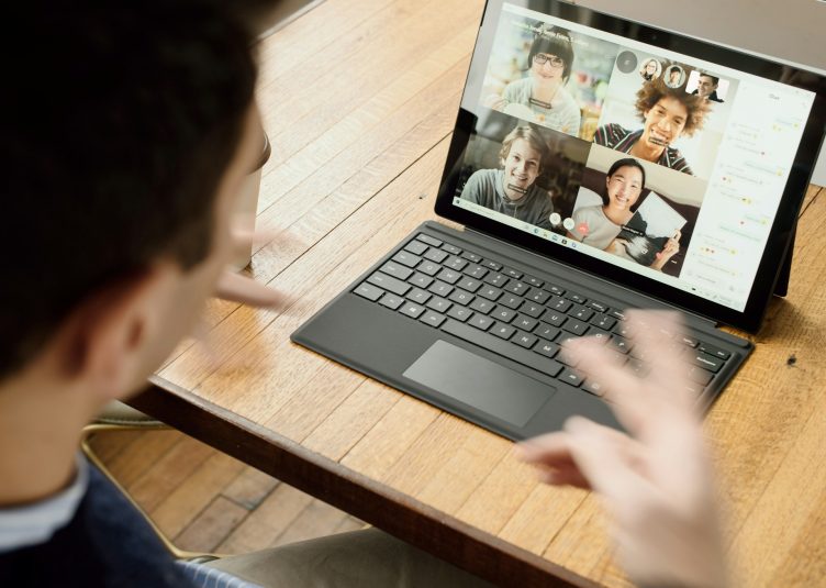a man talking to a group of people on a video call on a laptop