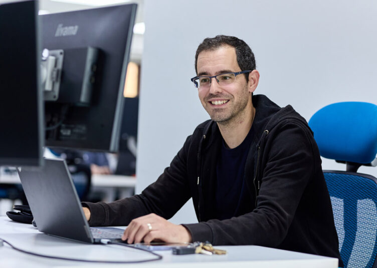 Our customer success team working at a desk, sitting on a blue desk chair. CYAN IT Service Provider